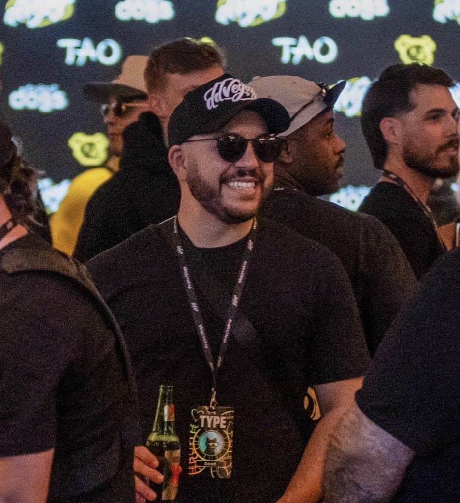 ScadMeta at TAO ScadMeta (@ScadMeta) in a black cap and sunglasses with a Type lanyard at a TAO event